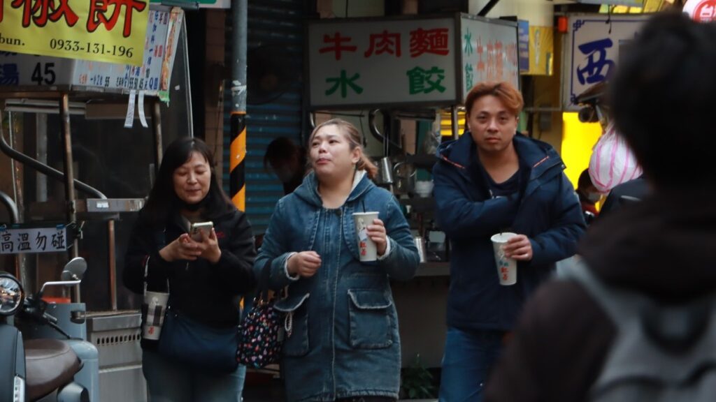 高頻率的含糖飲料攝取，往往集中於社經條件較弱族群。街頭民眾手持含糖飲料，反映日常高糖攝取情境。